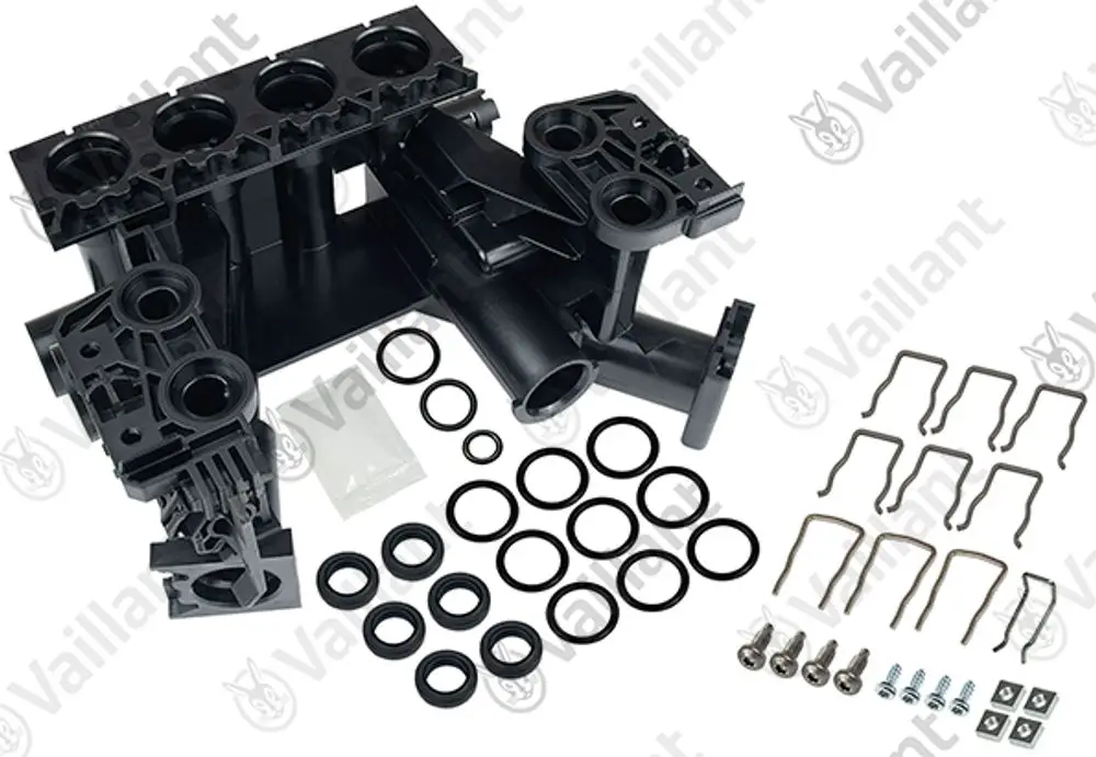 Vaillant Hydroblock mit mehreren Anschlüssen, umgeben von Dichtungsringen, Schrauben und Halteklammern, auf heller Fläche arrangiert.